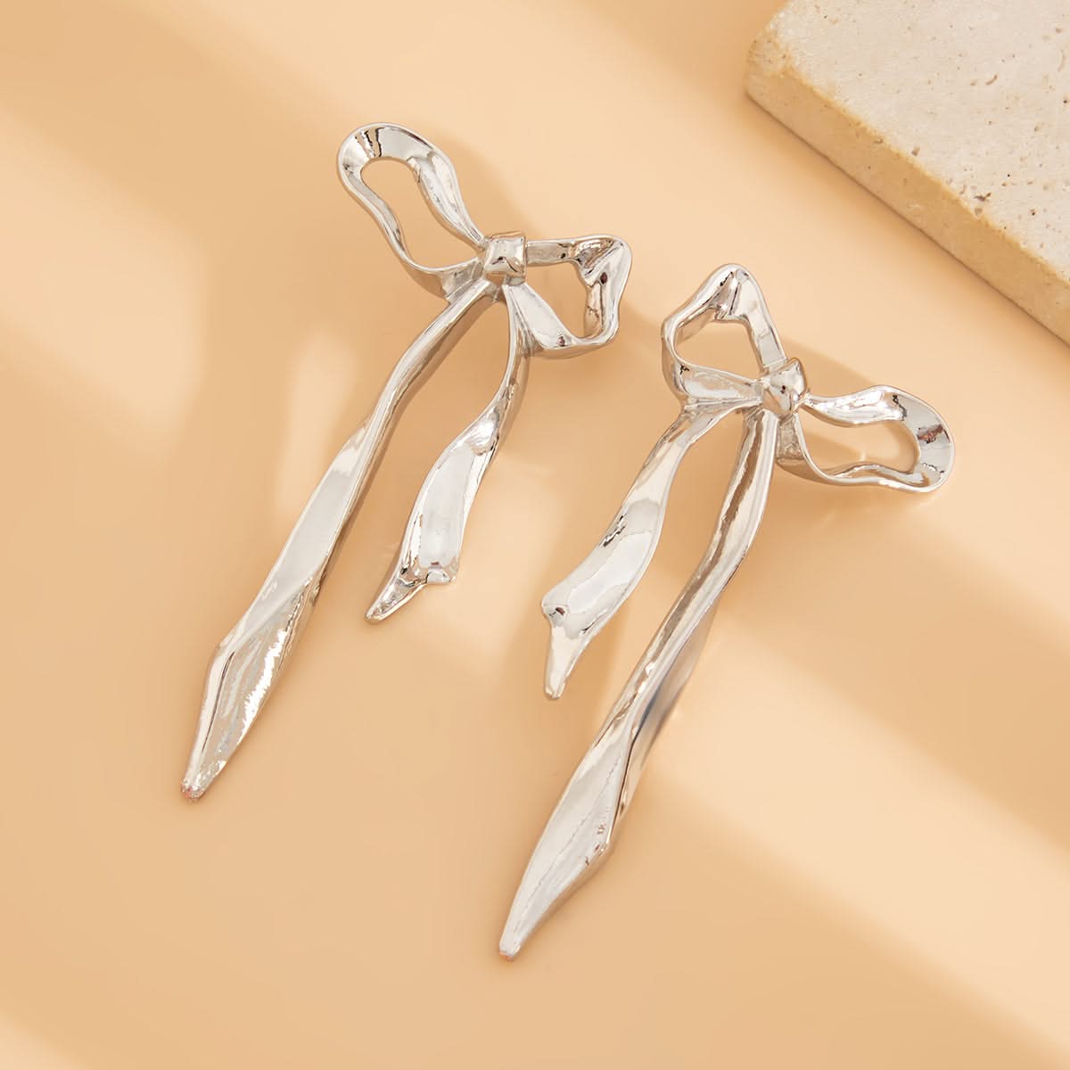 Elegant ribbon bow earrings. Gold-tone women's fashion accessory with a dainty, classic design. Versatile everyday jewelry.