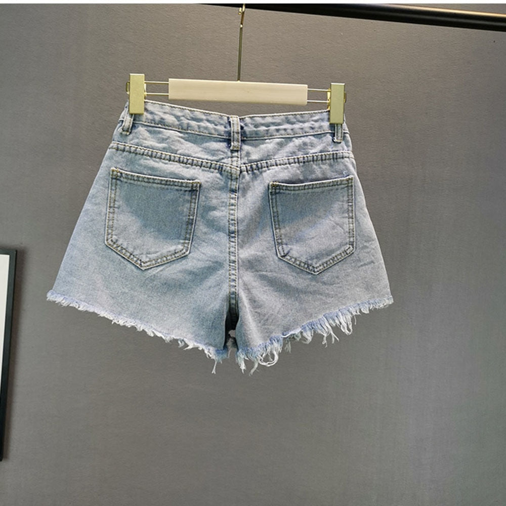 Fashionable women's shorts in light blue, adorned with subtle sparkly diamond accents for a stylish appeal.