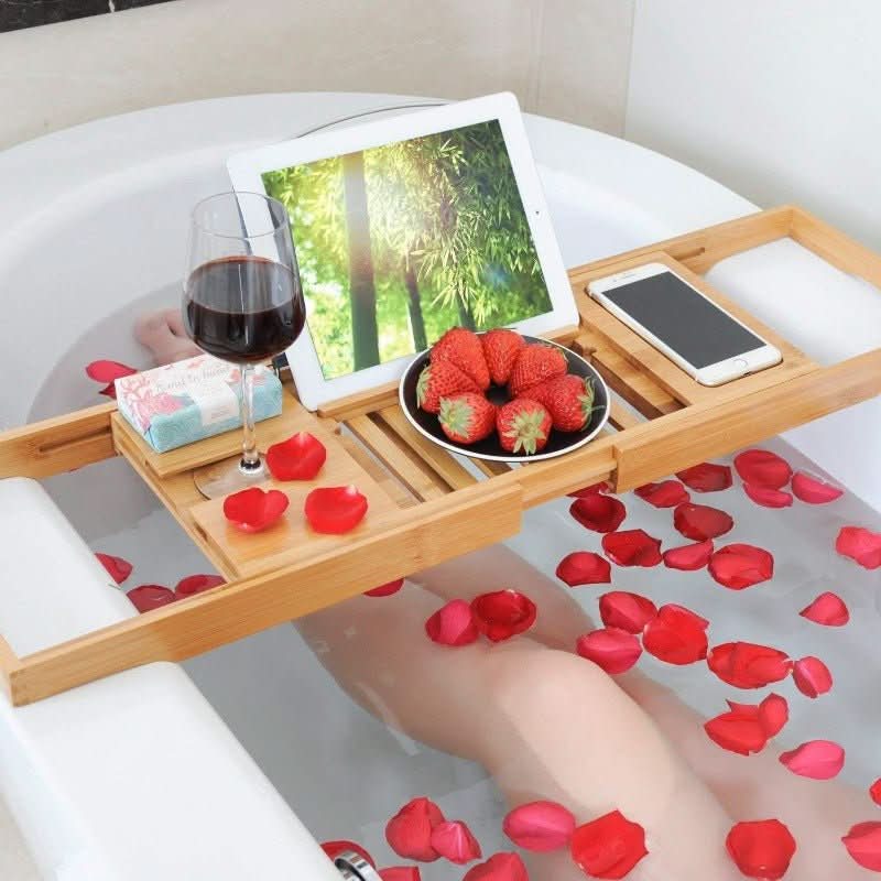 Natural bamboo adjustable bath caddy. Perfect for organizing bath essentials, enhancing self-care & relaxation.