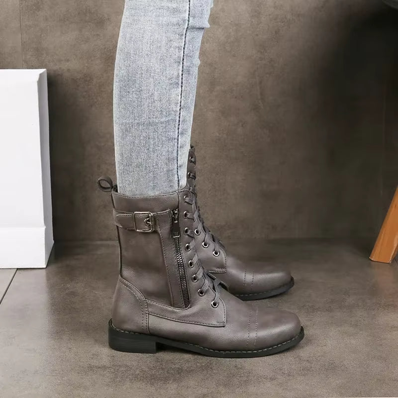 Women's black mid-calf boots with prominent buckles, lace-up design, & side zipper for an edgy look.