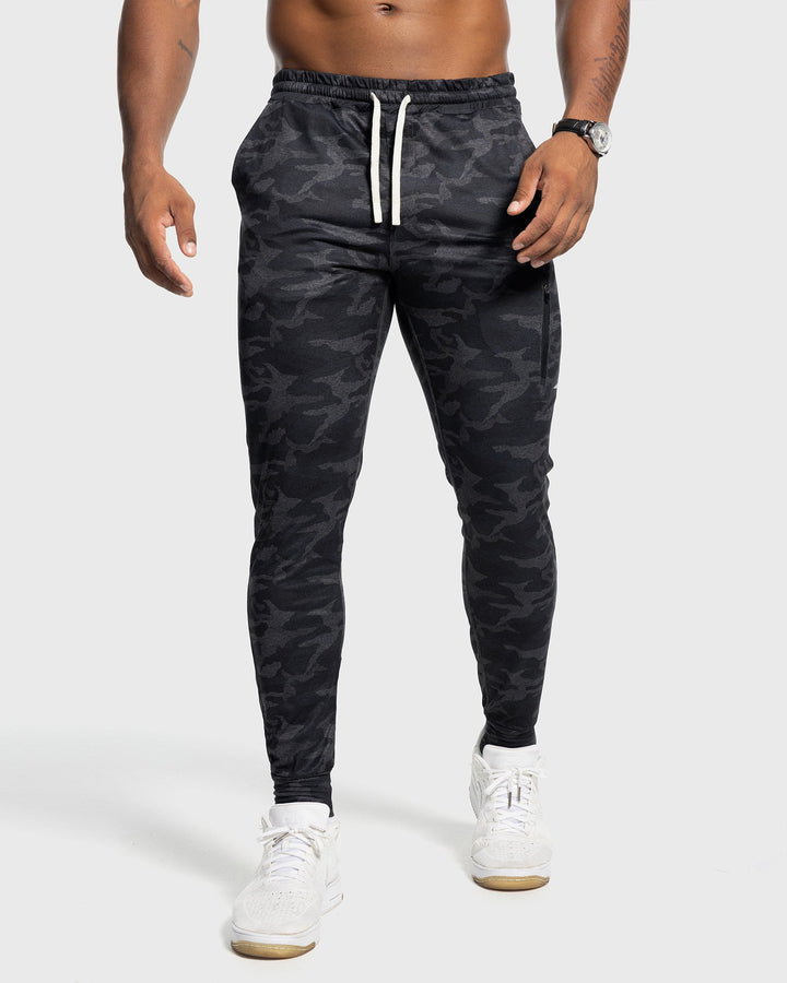 Men's stretch athletic pants, dark grey, performing a warm-up stretch.