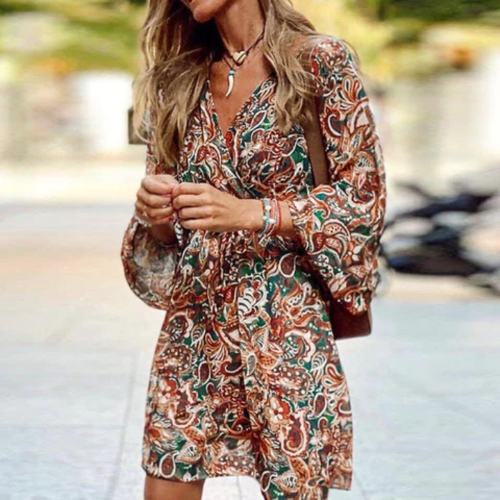 Flowy brown boho mini dress with a vibrant paisley print, V-neck, and stylish smock design. Ideal festival fashion.