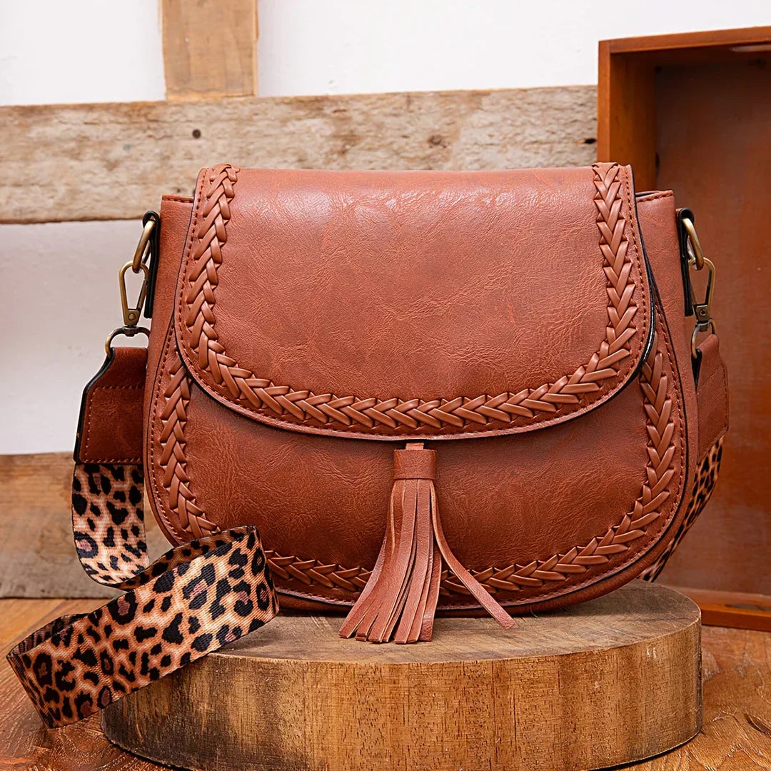 Chic brown women's saddle bag with elegant tassel detail. A versatile crossbody fashion accessory.