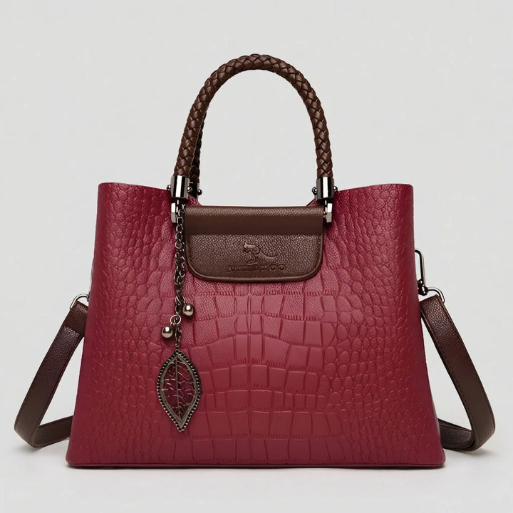 Fashionable women's red embossed tote bag featuring a chic braided handle. Versatile everyday shoulder bag.