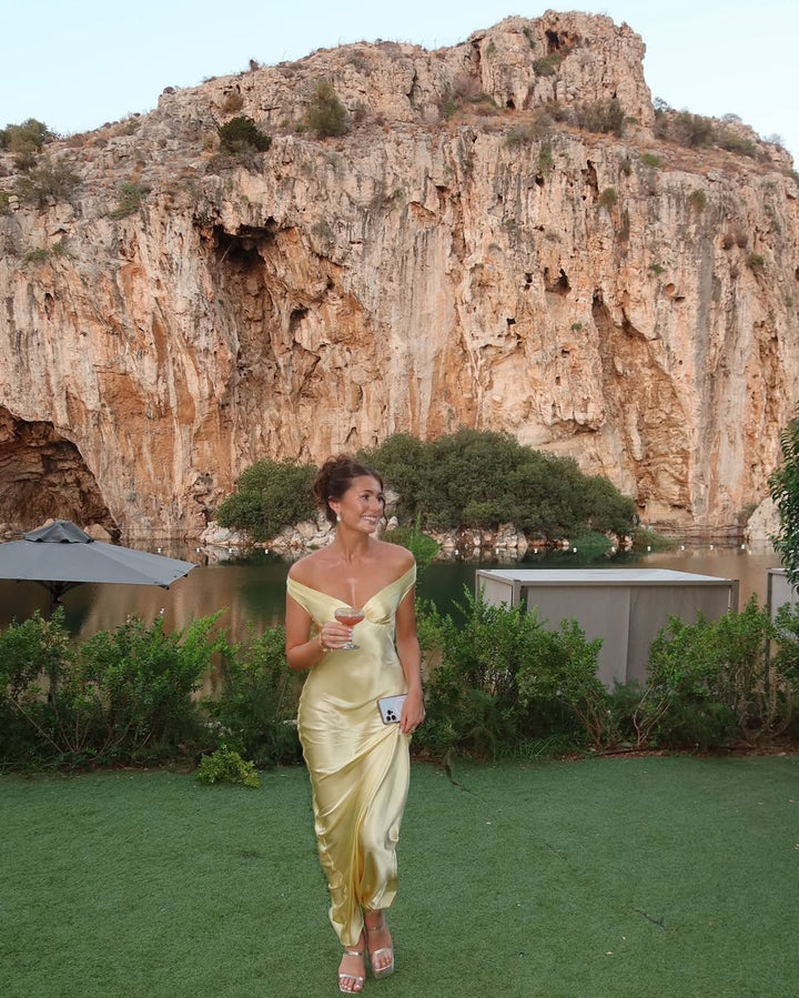 Stylish women's off-shoulder gold maxi dress. Chic formal evening gown with a bias cut, ideal for wedding guests.