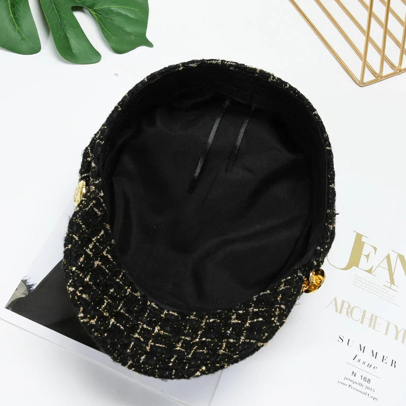 Elegant women's black tweed cap adorned with a luxurious gold chain, ideal for a polished look.