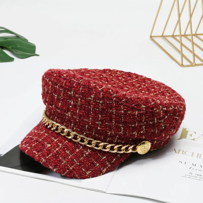 Structured women's tweed cap with a unique gold chain detail, a fashionable and chic headwear piece.