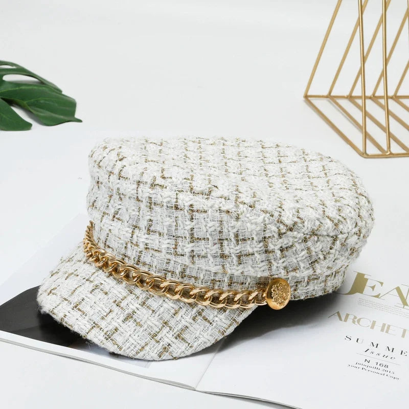 Sophisticated women's tweed cap, featuring a decorative gold chain, for a modern and stylish headwear choice.