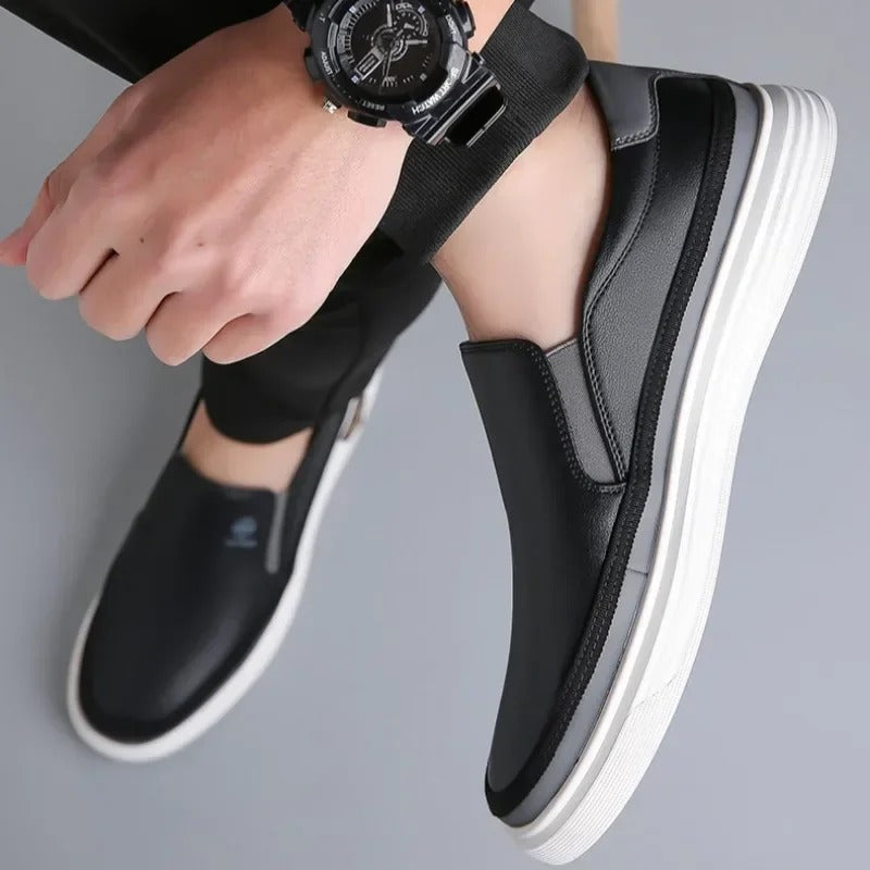 Close-up of men's sleek black leather slip-on shoes, showcasing fine craftsmanship & texture.