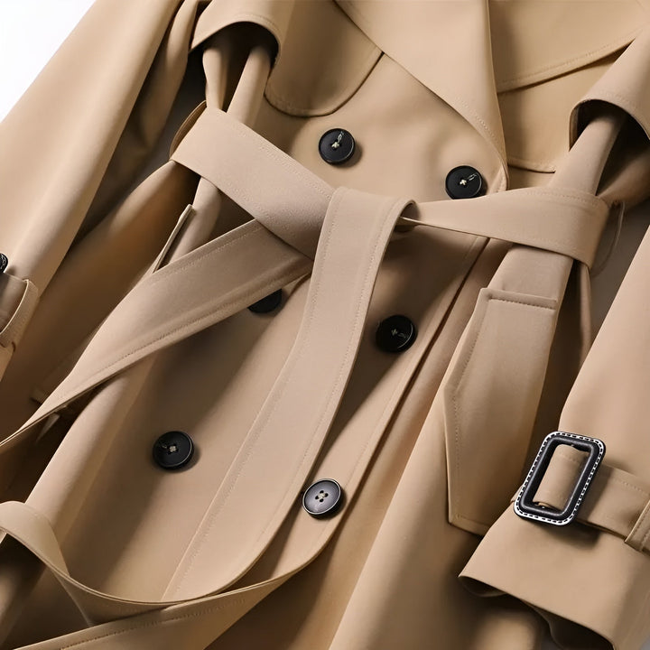 Smooth water-resistant fabric of a women's classic trench coat, double-breasted, with a stylish belt.