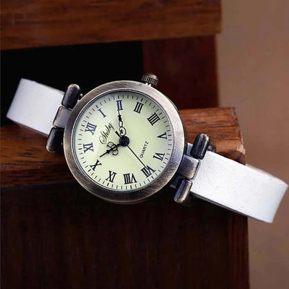 Overhead shot of women's vintage watch, leather strap, and minimalist dial on a neutral background.