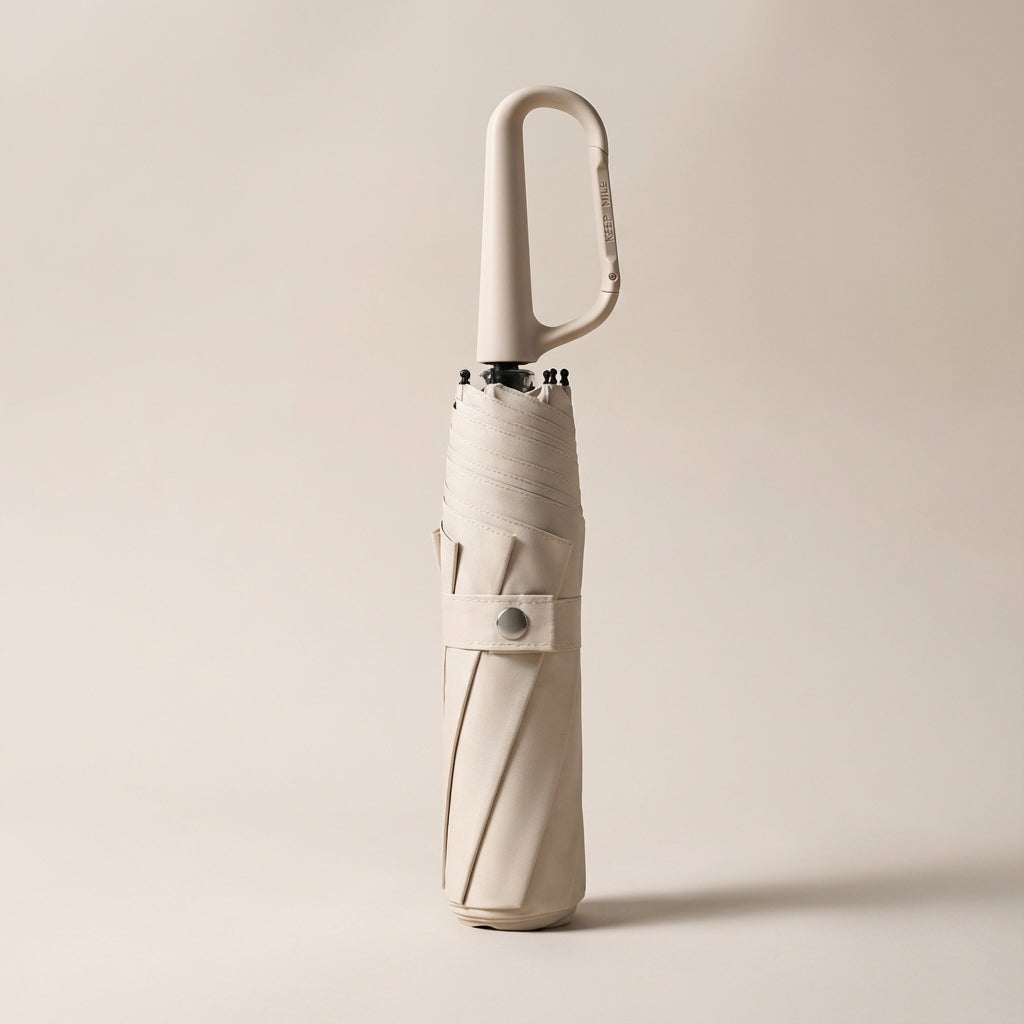Portable clip-on umbrella folded compactly, ready to attach to a backpack or purse for travel.