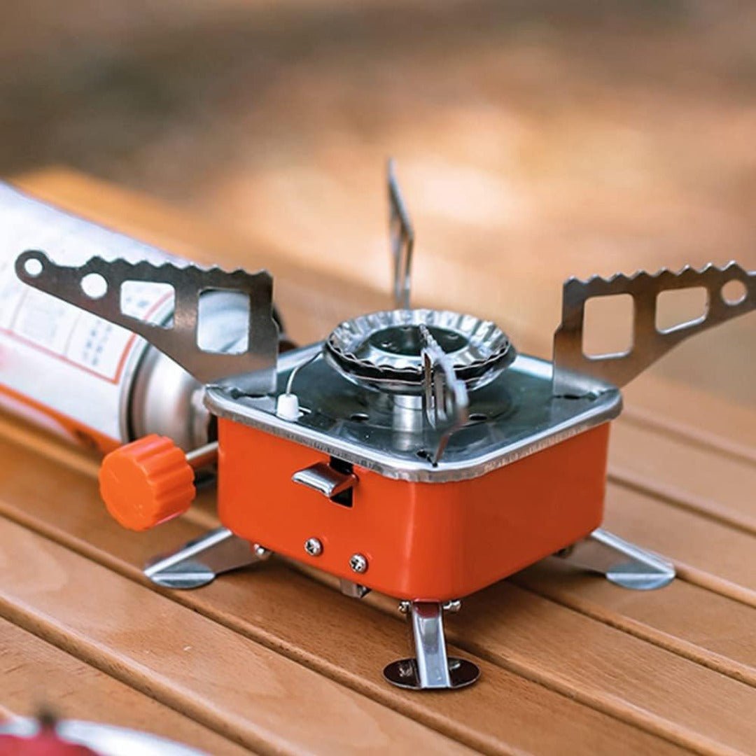Foldable gas stove for backpackers, showing its compact size next to an adult's hand, outdoor gear