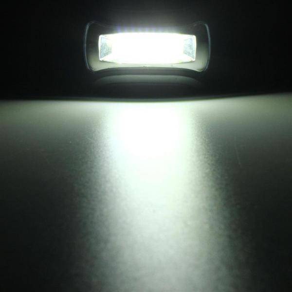 Close-up of a mini LED headlamp torch with illuminated COB light, showcasing its brightness & portability