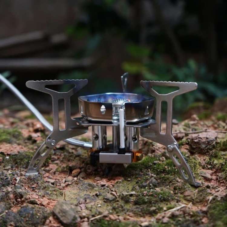 Portable gas stove in action, boiling water on a camping trip, showcasing its compact design for backpacking.