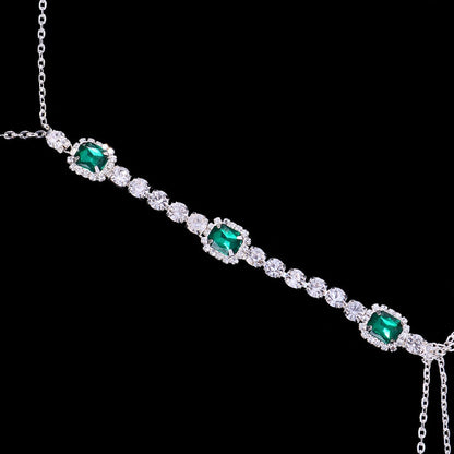 Green crystal chest chain for women. Dazzling rhinestone body jewelry, an elegant & sparkling statement accessory.