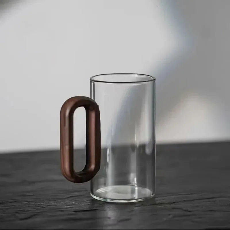 Modern transparent borosilicate glass mug featuring an ergonomic walnut handle. Ideal for coffee & tea.
