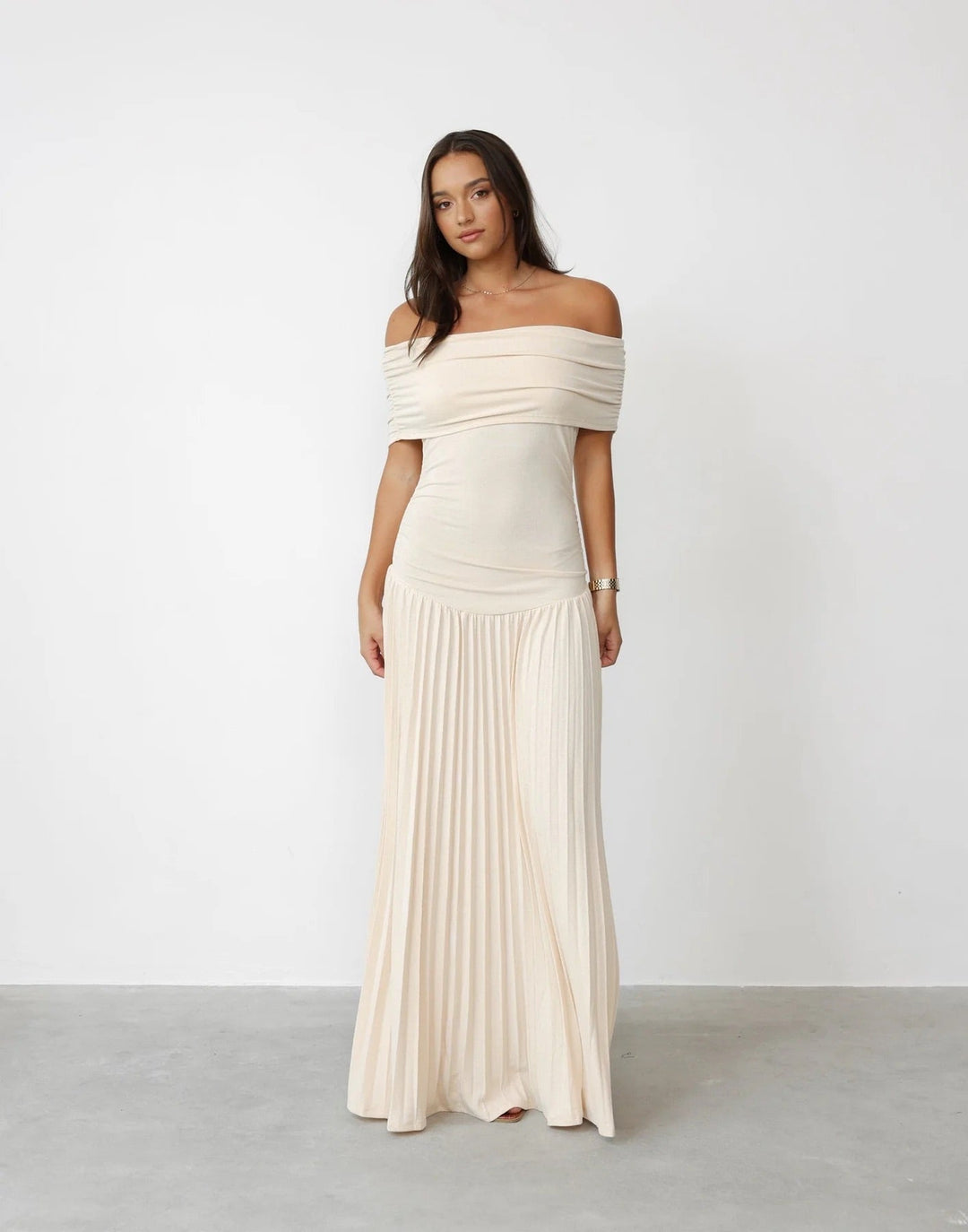 Elegant cream off-shoulder pleated maxi wedding guest dress.