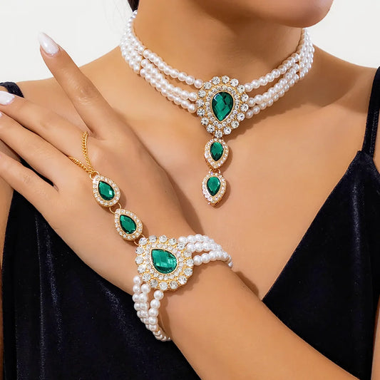 Elegant gold jewelry set for women, features necklace & bracelet with green & white gemstones.