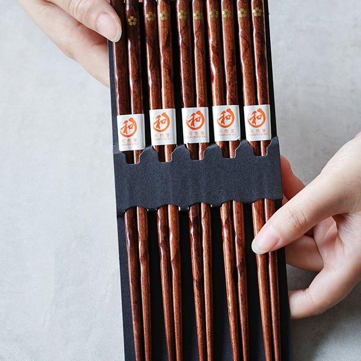 Close-up of elegant wooden chopsticks with intricate golden cherry blossom motif. Ideal Japanese dining tableware.
