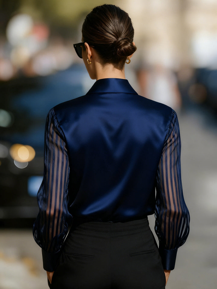 Close-up of elegant women's collared button-up top, showcasing the intricate patterned long sleeves and fabric.