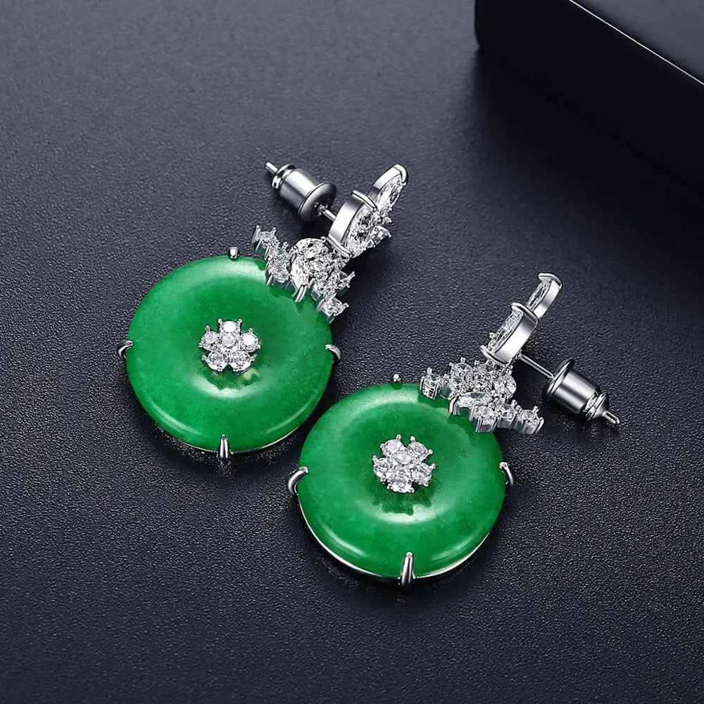 Luxury women's fashion earrings featuring vibrant emerald green gemstones on sleek stainless steel drop design.