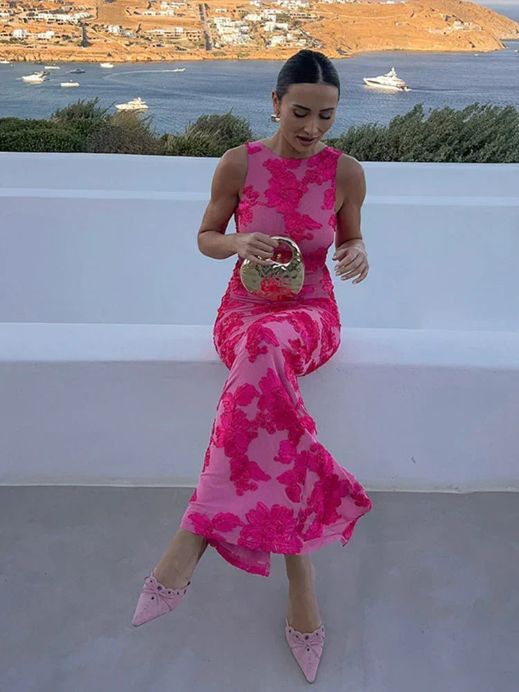 Fitted pink floral high-neck maxi wedding guest dress. Elegant sleeveless column gown for special occasion wear.