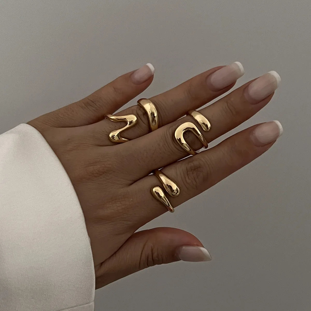 Close-up of a women's sculptural ring set featuring a unique fluid design, silver.