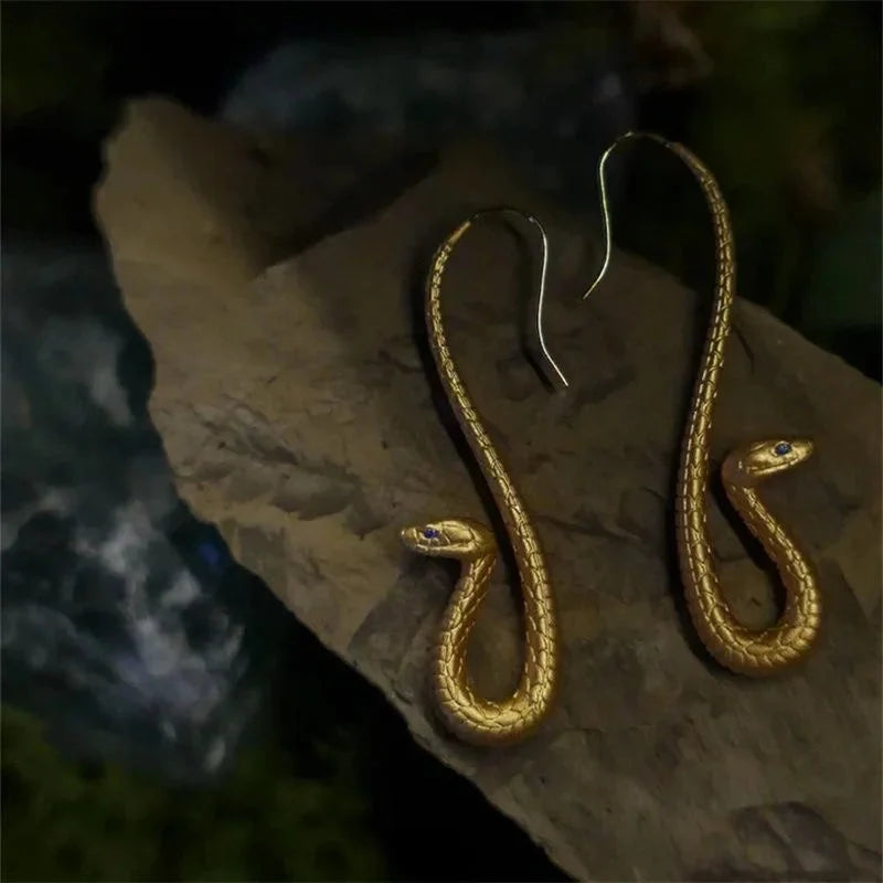 Statement golden serpent dangle earrings, a unique piece of women's jewelry and elegant fashion accessory.
