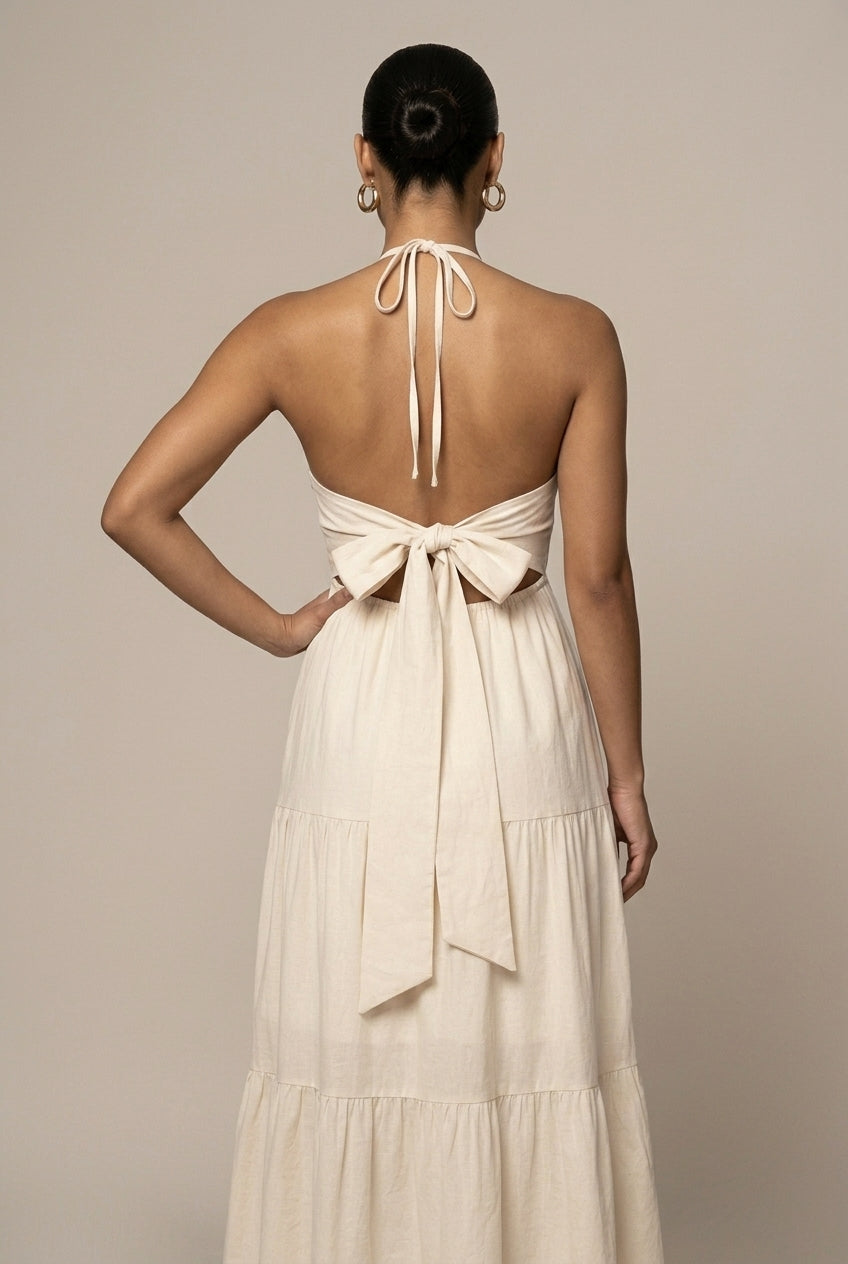 Flowy women's halter maxi dress featuring a tiered ruffle skirt, open back, & tie waist. Ideal for formal wear.