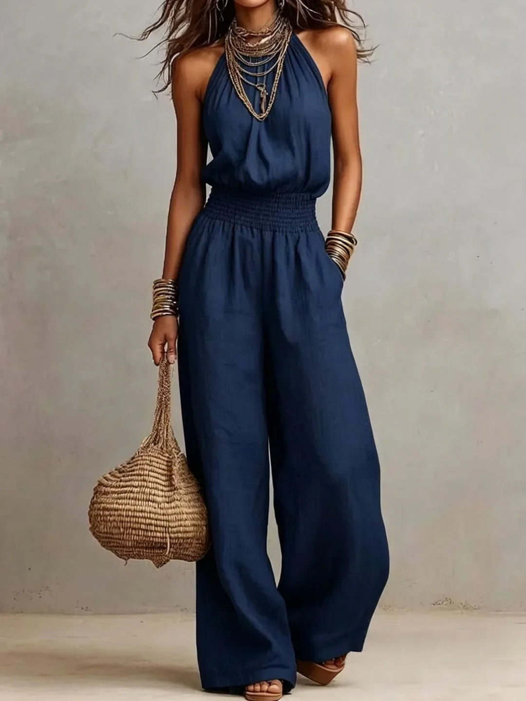 Chic women's halter neck wide leg jumpsuit with a flowy silhouette & smocked waist, perfect for stylish summer wear.