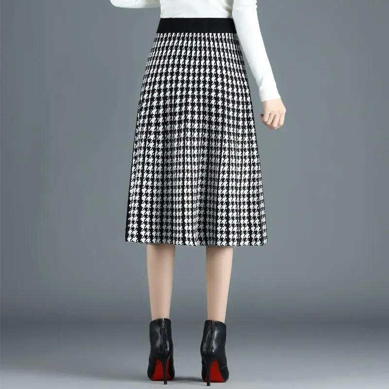 Versatile women's houndstooth midi skirt, elegantly pleated A-line style. High-waist chic apparel for work or fall fashion.