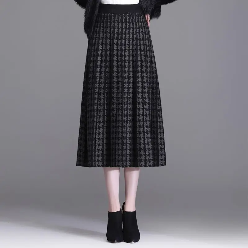 Stylish women's pleated A-line midi skirt in classic houndstooth print. High-waist, elegant for fall and workwear.