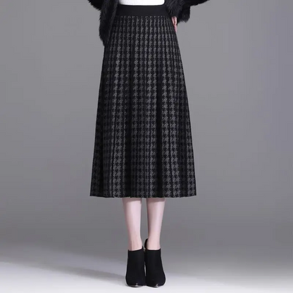 Stylish women's pleated A-line midi skirt in classic houndstooth print. High-waist, elegant for fall and workwear.