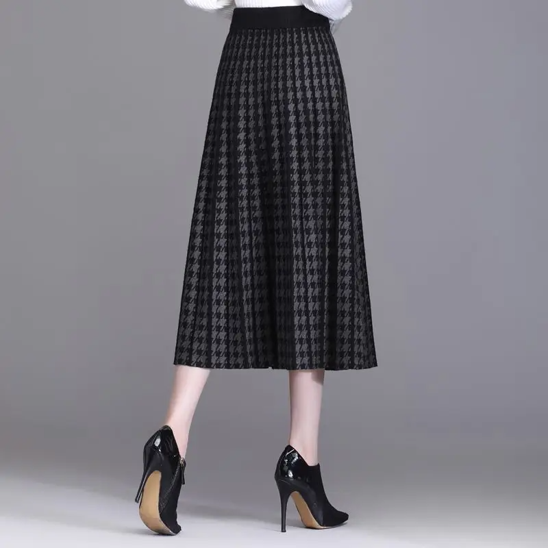 Fall fashion women's houndstooth midi skirt, elegantly pleated and high-waisted. Chic A-line style, versatile apparel.