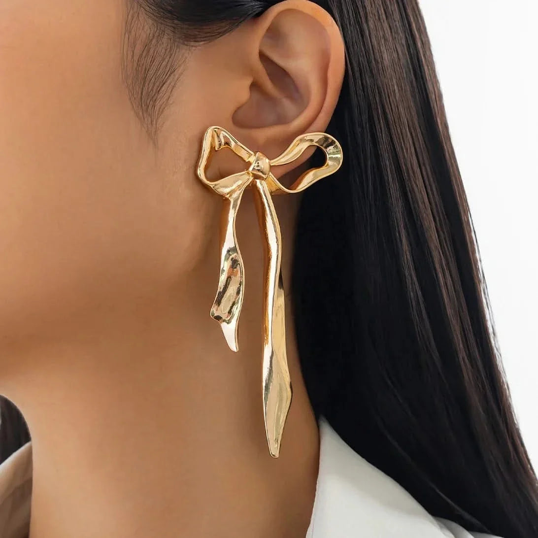 Stylish women's ribbon bow earrings. Elegant and dainty, ideal for adding a touch of classic charm to any outfit.