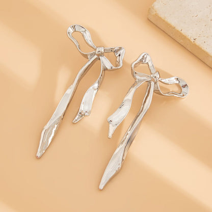 Elegant ribbon bow earrings. Gold-tone women's fashion accessory with a dainty, classic design. Versatile everyday jewelry.