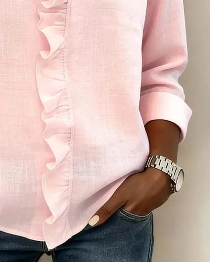 Woman seated wearing an elegant ruffled V-neck long sleeve blouse, showcasing its comfortable and versatile design.