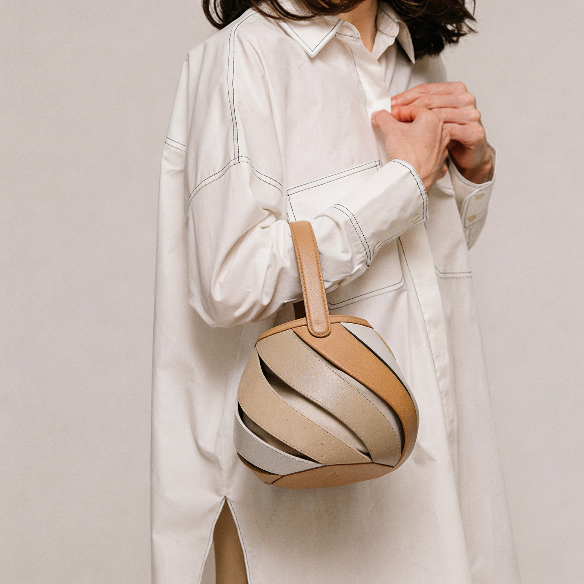 Detailed spiral cage design on an elegant women's bucket bag, a unique and stylish top-handle handbag.