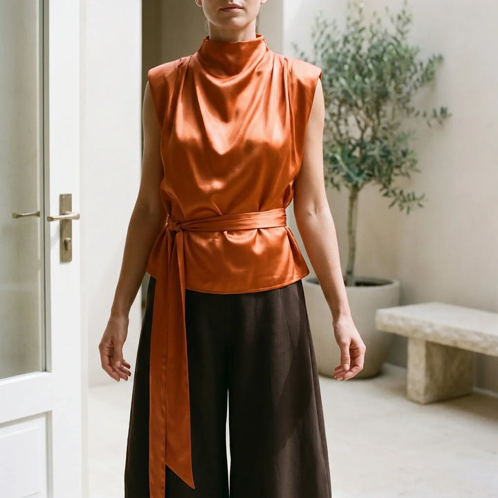 Elegant women's textured cowl neck sleeveless blouse with adjustable tie-waist, perfect for evening wear.