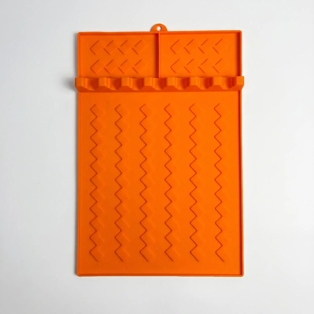 Flexible grill utensil rest with multiple slots, neatly holding tongs, spatulas, and brushes for tidy outdoor cooking.