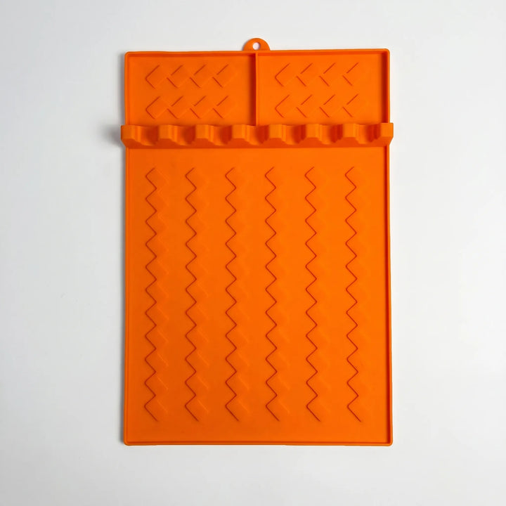 Flexible grill utensil rest with multiple slots, neatly holding tongs, spatulas, and brushes for tidy outdoor cooking.