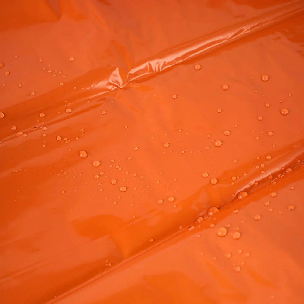 Close-up of a folded orange emergency sleeping bag, 4-pack, highlighting compact design for survival gear.