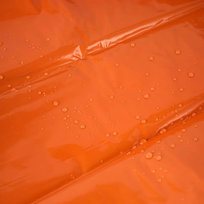 Close-up of a folded orange emergency sleeping bag, 4-pack, highlighting compact design for survival gear.