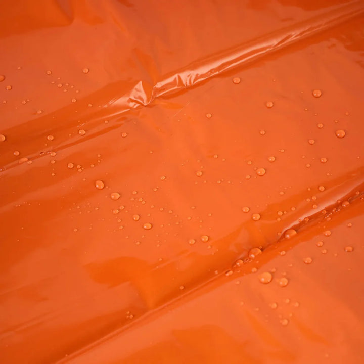 Close-up of a folded orange emergency sleeping bag, 4-pack, highlighting compact design for survival gear.