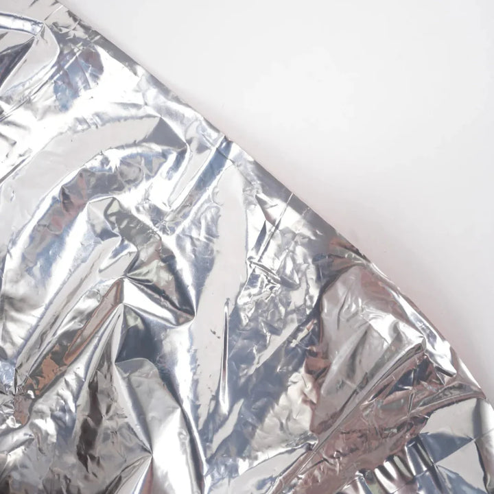 Emergency survival sleeping bags (4-Pack) laid out, showcasing their reflective mylar material for outdoor safety.