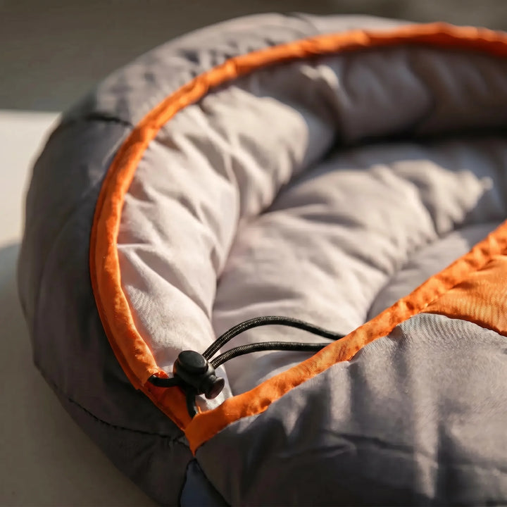 Comfortable green & orange envelope sleeping bag for 4-season camping. Durable, warm outdoor gear for adventurers.
