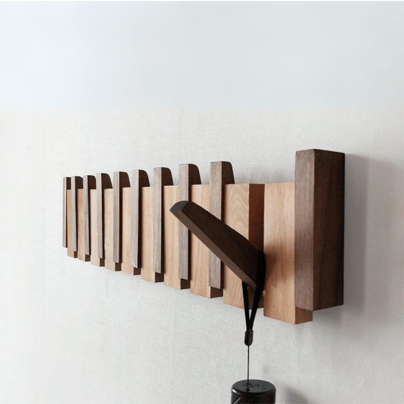 Handmade wooden entryway coat rack with innovative folding hooks, a sleek storage solution.