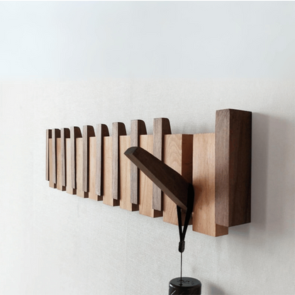 Handmade wooden entryway coat rack with innovative folding hooks, a sleek storage solution.