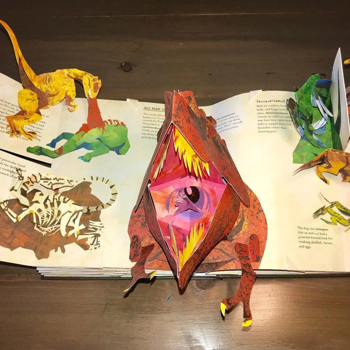Child's hand pointing at a fact in a 3D dinosaur pop-up book, promoting learning & STEM education. Prehistoric facts.